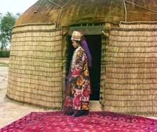 Turkman woman standing at the entry to a grass and hide covered yurt. Collection of the Library of Congress Prints and Images File